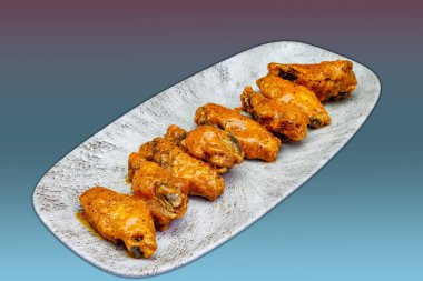 Morumsu ve açık mavi arka planda Bufalo soslu tavuk kanadı kompozisyonu.