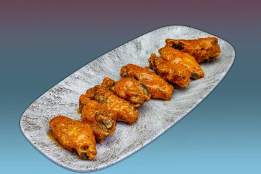 Morumsu ve açık mavi arka planda Bufalo soslu tavuk kanadı kompozisyonu.