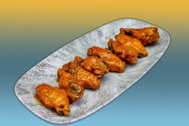 Sarı ve açık mavi arkaplanda Bufalo soslu tavuk kanadı kompozisyonu