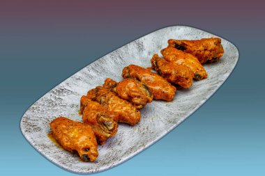 Morumsu ve açık mavi arka planda Bufalo soslu tavuk kanadı kompozisyonu.