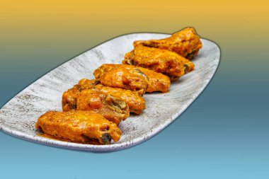 Sarı ve açık mavi arkaplanda Bufalo soslu tavuk kanadı kompozisyonu