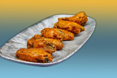 Sarı ve açık mavi arkaplanda Bufalo soslu tavuk kanadı kompozisyonu