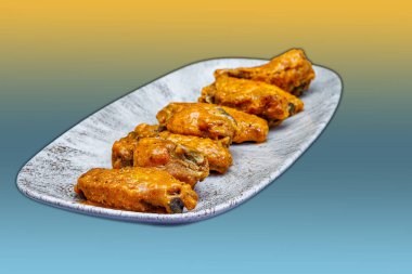 Sarı ve açık mavi arkaplanda Bufalo soslu tavuk kanadı kompozisyonu