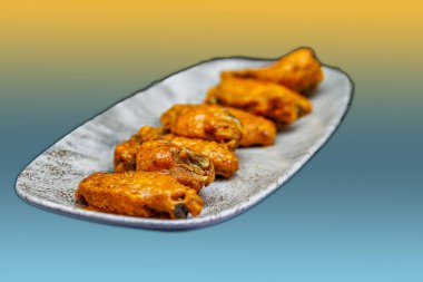 Sarı ve açık mavi arkaplanda Bufalo soslu tavuk kanadı kompozisyonu