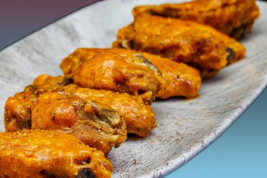 Morumsu ve açık mavi arka planda Bufalo soslu tavuk kanadı kompozisyonu.