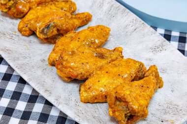 Siyah beyaz kareli masa örtüsü üzerine bufalo soslu tavuk kanadı kompozisyonu.