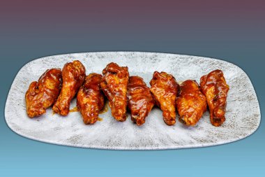 Pembe üzerine barbekü sosu ve açık mavi gradyan arkaplan ile bir tabak tavuk kanadı bileşimi