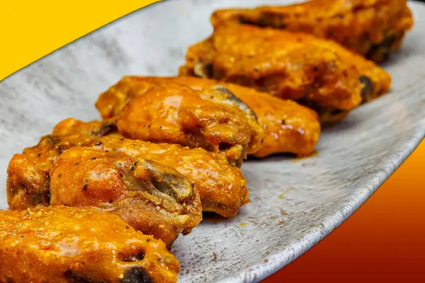 Composition of a dish of chicken wings with Buffalo sauce on a red and yellow background