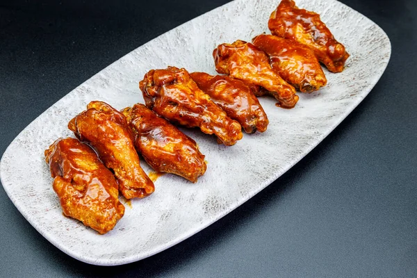 Composition of a plate of chicken wings with barbecue sauce on black background