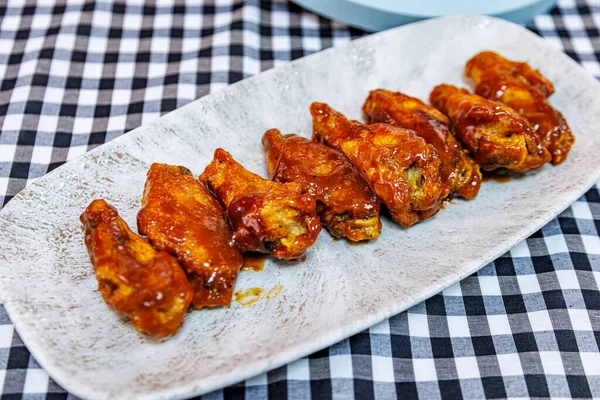 Composition of a plate of chicken wings with barbecue sauce on a black and white checkered tablecloth