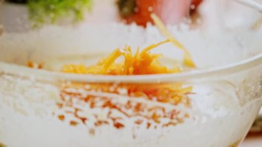 Baker cam bir kasede malzemeleri karıştırıyor. Kadın hamura ızgara balkabağı ekliyor. Ev yapımı kek tarifi. 4k görüntü