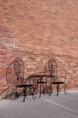 Table and chairs at an ld brick storefront in downtown Granum. clipart