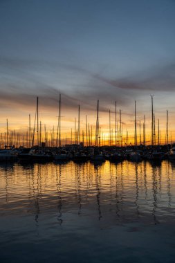 Valencia limanındaki deniz suyuna yansıyan yatlar. İskele vinçleri ufukta. İspanya 'da sıcak bir akşam.