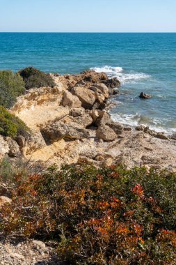 Güçlü bir rüzgarla İspanya denizindeki kayalar. Beyaz su sıçratan dalgalar kıyıya çarpıyor. güneşli bahar günü
