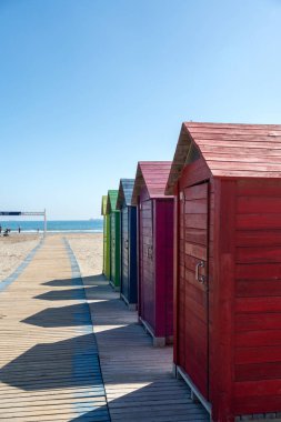 Baharda İspanya 'da deniz kıyısında esen rüzgar. Kumsaldaki parlak renkli plaj evleri. Castellon