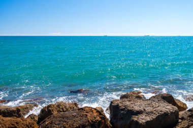 Güçlü bir rüzgarla İspanya denizindeki kayalar. Beyaz su sıçratan dalgalar kıyıya çarpıyor. güneşli bahar günü