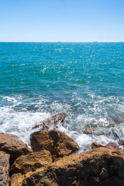 Güçlü bir rüzgarla İspanya denizindeki kayalar. Beyaz su sıçratan dalgalar kıyıya çarpıyor. güneşli bahar günü