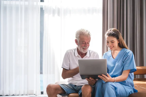 Asian Nurse Caregiver Teaching Senior Caucasian Man Handle Digital Laptop Стокове Зображення
