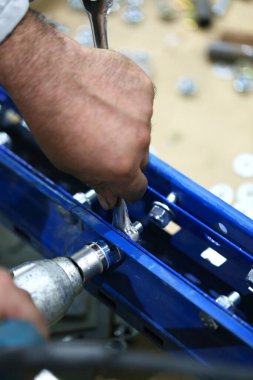 Ereksiyon sırasında elektrikli aletlerle vidaları sıkan bir depo işçisi