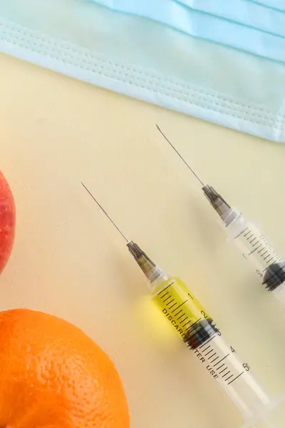 食品や遺伝子組み換え果物の概念に化学添加物 化学物質の注射器と赤いリンゴ 赤色の背景に隔離された — ストック写真