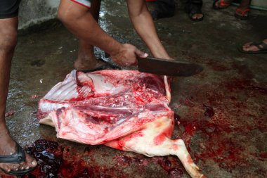 Kasap mezbahada bıçakla çiğ et kesiyor.
