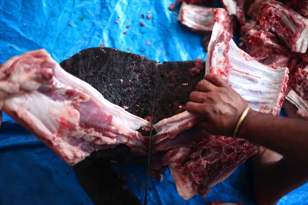 stock image Butcher cutting raw meat  with a knife at table in slaughterhouse