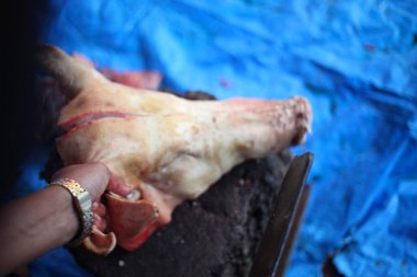 Kasap mezbahada bıçakla çiğ et kesiyor.