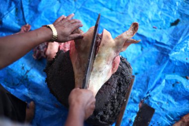 Kasap mezbahada bıçakla çiğ et kesiyor.