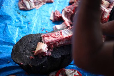 Kasap mezbahada bıçakla çiğ et kesiyor.