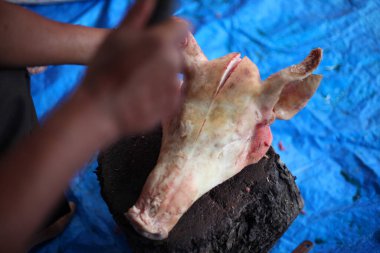 Kasap mezbahada bıçakla çiğ et kesiyor.