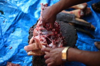 Kasap mezbahada bıçakla çiğ et kesiyor.