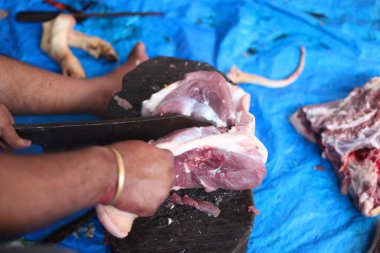 Kasap mezbahada bıçakla çiğ et kesiyor.