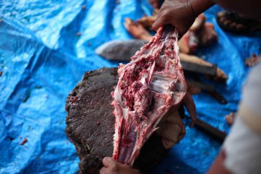 Kasap mezbahada bıçakla çiğ et kesiyor.