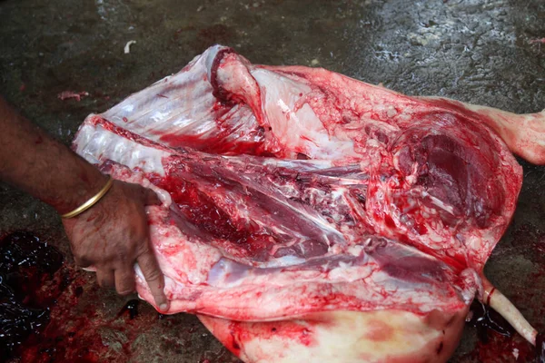 Kasap mezbahada bıçakla çiğ et kesiyor.