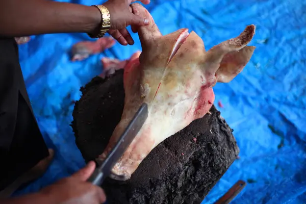 stock image Butcher cutting raw meat  with a knife at table in slaughterhouse