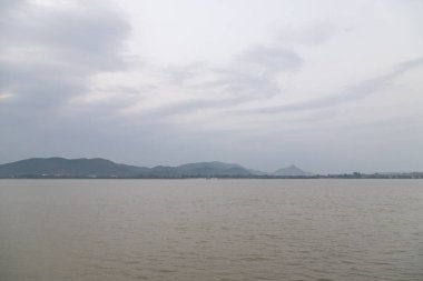 Guwahati, Assam, Hindistan 'daki Brahmaputra nehri üzerinde dağlarla gün batımının manzarası.