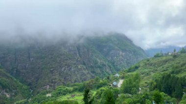 Jang kasabasındaki dağların üzerinden fırtına bulutları Arunachal Pradesh 'in Tawang bölgesindeki Jang Vadisi' nin derinliklerinde ve Hindistan 'ın Arunachal Pradesh şehrinde yağmurlu bir günde yüksek dağlarla çevrili..