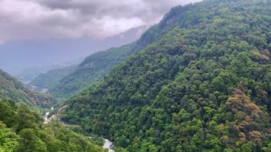 Jang kasabasındaki dağların üzerinden fırtına bulutları Arunachal Pradesh 'in Tawang bölgesindeki Jang Vadisi' nin derinliklerinde ve Hindistan 'ın Arunachal Pradesh şehrinde yağmurlu bir günde yüksek dağlarla çevrili..