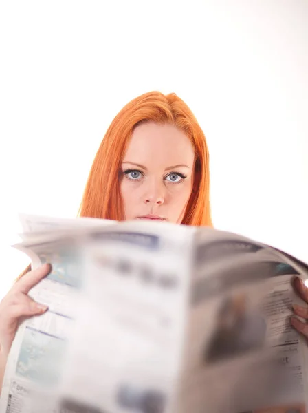 Woman with red hair readind a newspaper shot in studio with white background