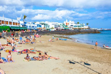 Playay Blanca, İspanya - 5 Nisan 2012: İnsanlar Playa Blanca, İspanya 'daki Playa Dorada plajının tadını çıkarıyorlar. Plaj 2010 yılında beyaz kumla restore edildi ve Lanzarote 'un en üst plajı oldu..