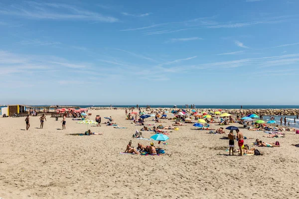 SAINTES MARIES DE LA MER, FRANCE - 15 AUG 2017: İnsanlar sıcak bir yaz gününde kumsalın tadını çıkarırlar, Camargue 'deki plaj 10 mil boyunca uzanıyor..