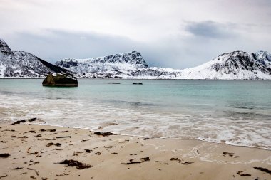 Norveç 'in Lofoten Adaları' ndaki Nusfjord kasabası yakınlarındaki sahil, okyanus ve dağlarla manzaralı bir yer.