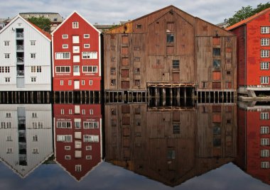 Norveç 'in Trondheim kentindeki Brygge bölgesinde Nidelva nehrinde yansıyan eski renkli ahşap evlerin geniş panoramik manzarası