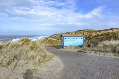 List, Germany - February 16, 2022: scenic landscape in Sylt with ocean, dune and empty beach hut in spring time. clipart