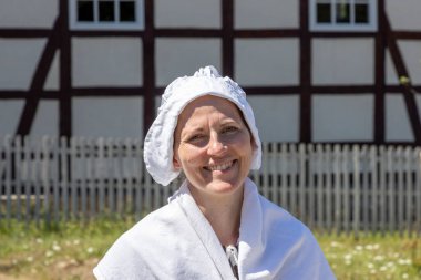 Neu Anspach, Germany - August 6, 2020: young attractive woman in old traditional clothes demonstrates former traditional clothing in the Hessenpark in Germany.