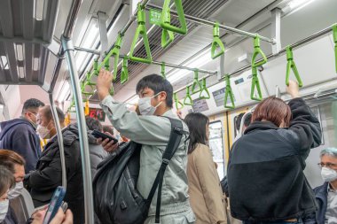 Tokyo, Japonya - 16 Mart 2023: Tokyo 'da metro kullanan ve hastalıktan korunmak için maske takan insanlar. Metro 'da insanlar bekliyor..