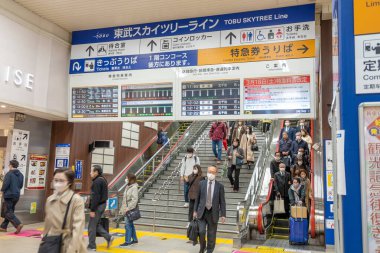 Tokyo, Japonya - 17 Mart 2023: Tokyo metro istasyonundaki insanlar. Japonca ve İngilizce imzalar turistlere metronun yönünü ve zamanını gösteriyor..