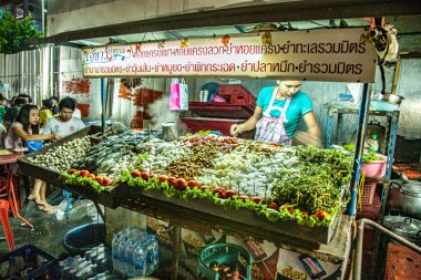 Bangkok, 6 Mayıs 2009: Caddedeki gece kulübesinde taze sebze, erişte ve çay satan kadın. Benzinle yemek yapıyor..