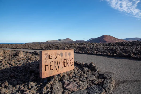 西班牙加那利群岛兰萨罗特市蒂曼法亚国家公园粗糙熔岩背景下的Los Hervideros金属标志 — 图库照片