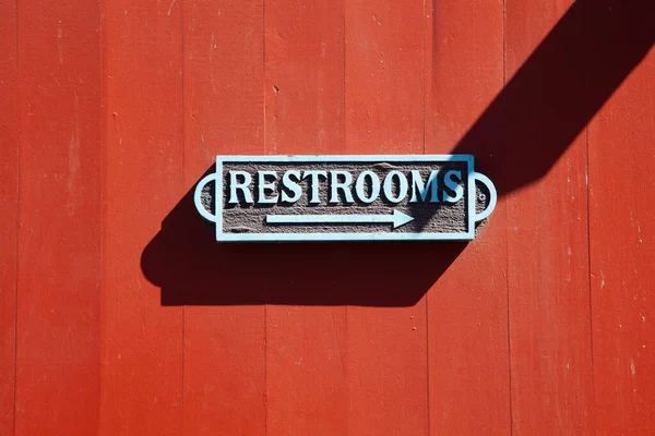 Gölgeli Kırmızı Bir Duvarda Metal Tuvaleti Imzala — Stok fotoğraf